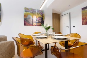 A dining area with a wooden table, orange chairs, and a painting on the wall. - Elegant 3BD Apartment in Valladolid Solanilla II (Valladolid)