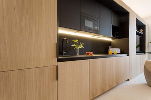 A modern kitchen with wooden cabinets, a black countertop, a microwave, and a vase with flowers. - Bright Apartment in the Heart of Valladolid Solanilla IV (Valladolid)