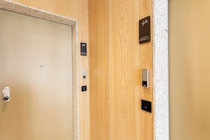A hotel room entrance with a wooden door, a keycard reader, a keypad, and a sign indicating room number 1A. - Bright Apartment in the Heart of Valladolid Solanilla IV (Valladolid)
