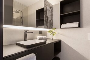 A modern bathroom with a large mirror, a rectangular sink, a towel, and a vase with a plant. - Bright Apartment in the Heart of Valladolid Solanilla IV (Valladolid)