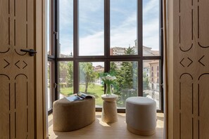 A room with large windows, a wooden door with geometric cutouts, and two ottomans. - Bright Apartment in the Heart of Valladolid Solanilla IV (Valladolid)