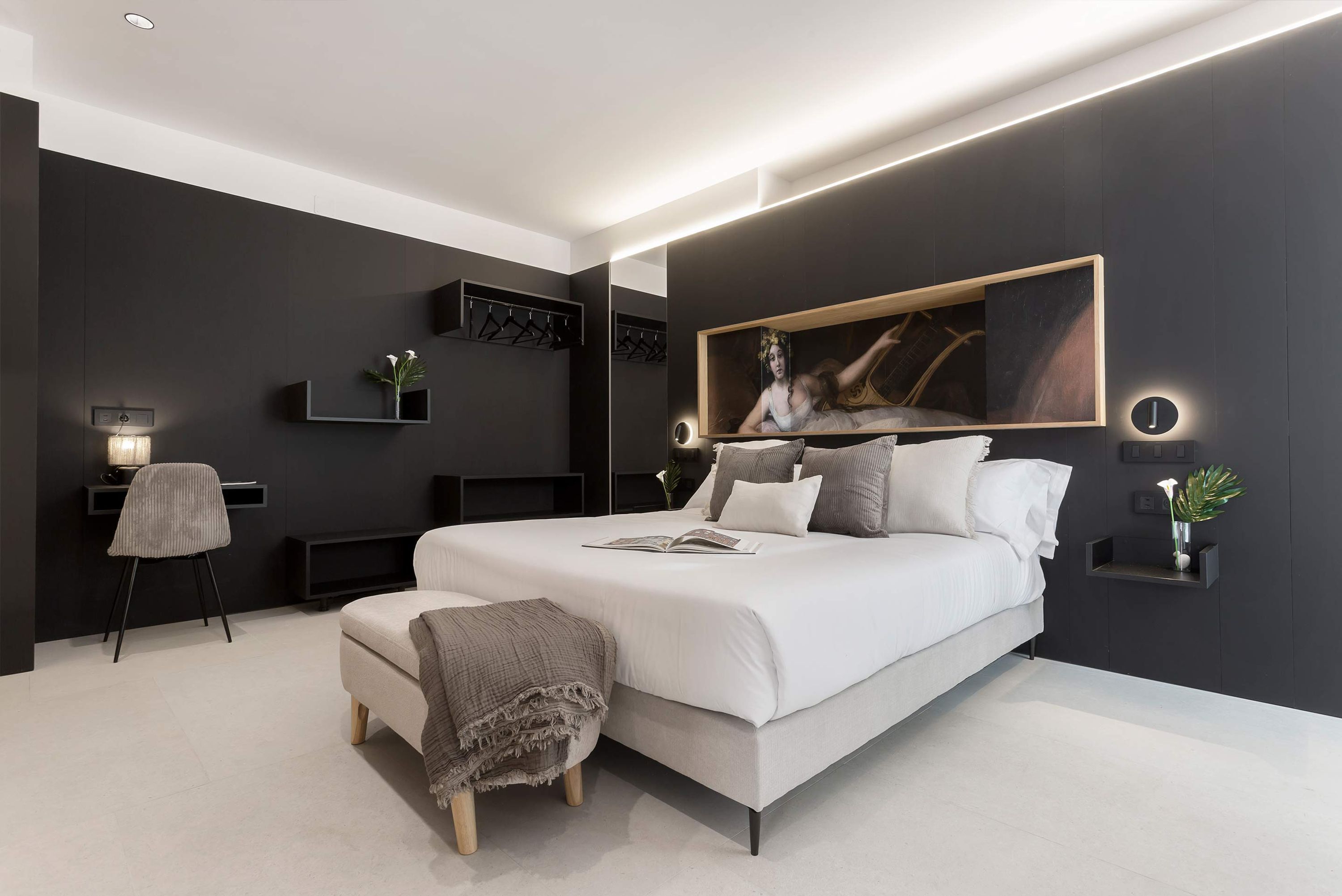 A modern bedroom with a large bed, bedside tables, a desk, and a chair.
