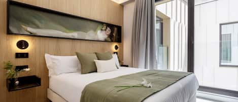 Un dormitorio moderno con una cama grande, un cuadro colgado en la pared, mesitas de noche y vistas al exterior.