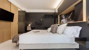 Un dormitorio moderno con una cama grande, un televisor montado y un cuadro en la pared.
