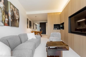 A modern living room with a grey sofa, a glass coffee table, and a flat-screen TV mounted on the wall. - Spectacular Apartment in Valladolid Center Solanilla III (Valladolid)