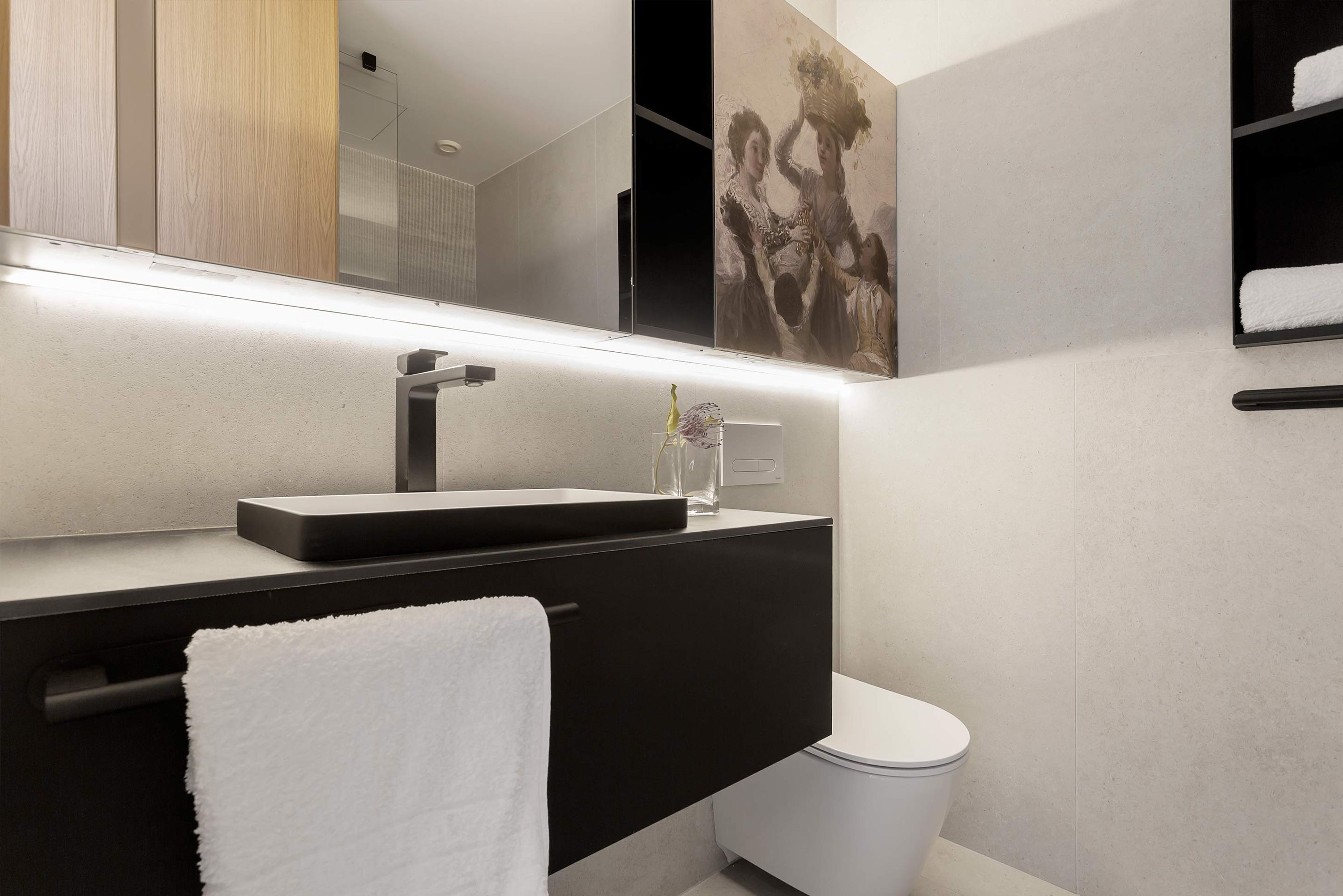 A modern bathroom with a black vanity, a white toilet, and a large mirror.