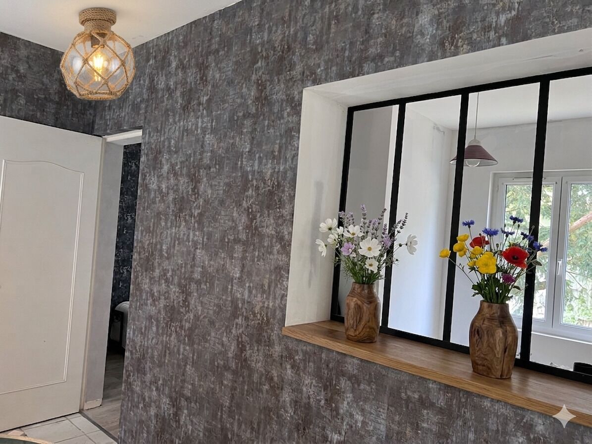 Un interior moderno con una pared texturizada, una repisa de madera con jarrones de flores, y un espejo grande que refleja una ventana.