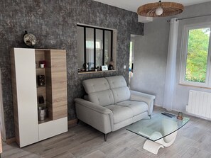 A modern living room with a grey sofa, a glass coffee table, a built-in wardrobe, and a large mirror. - Maison de vacances pour 6 personnes à 100 m de la plage (Saint-Georges-de-Didonne)