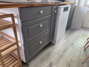 A kitchen with grey cabinets, a wooden countertop, and a built-in dishwasher. - Maison de vacances pour 6 personnes à 100 m de la plage (Saint-Georges-de-Didonne)