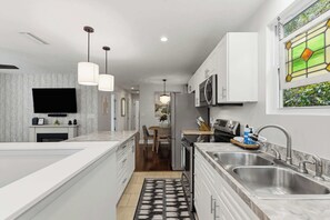 A modern kitchen with a large island, stainless steel appliances, and pendant lighting. - The Cottage Nook l Hot Tub l Mins to DNTN (St. Augustine)