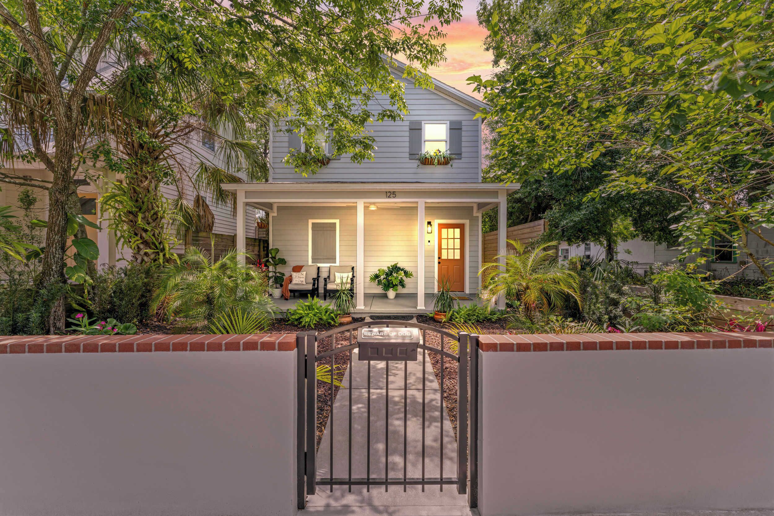 A two-story house with a front porch, a gated entrance, and a well-maintained garden.
