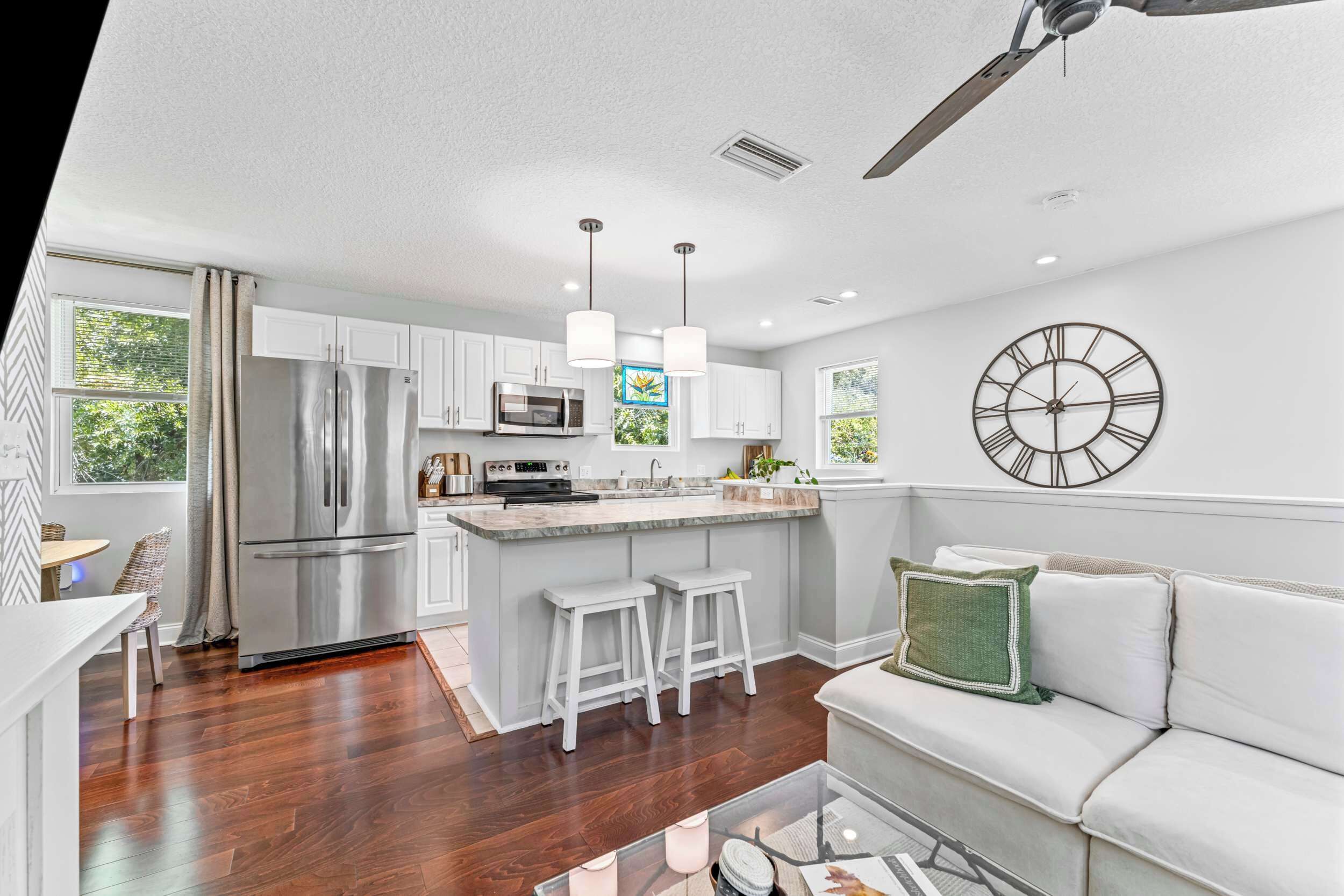 A modern kitchen with white cabinets, stainless steel appliances, and a bar area.