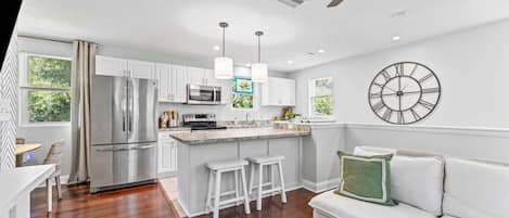 A modern kitchen with white cabinets, stainless steel appliances, and a bar area.