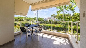 Ein Balkon mit Tisch und Stühlen, einem weißen Geländer und Blick auf Grünflächen und Gebäude.