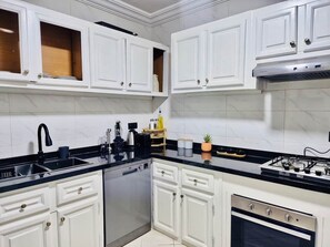 A kitchen with white cabinets, a black countertop, a dishwasher, a stove, and a sink. - In the heart of Gueliz (Central and cozy) + Netflix (Marrakesh)