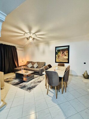 A modern living room with a sofa, coffee table, dining table, and chairs. - In the heart of Gueliz (Central and cozy) + Netflix (Marrakesh)