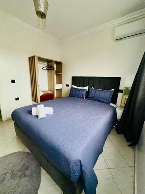 A hotel room with a bed, a wardrobe, a bedside table, and an air conditioning unit. - In the heart of Gueliz (Central and cozy) + Netflix (Marrakesh)