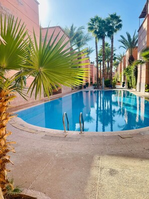 Ein Swimmingpool, umgeben von Palmen und Gebäuden.