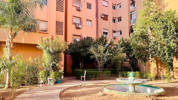 A courtyard with a fountain, palm trees, and a building with multiple balconies.