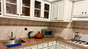 Una cucina con mobili bianchi, un piano cottura a gas, un forno a microonde e un lavello.