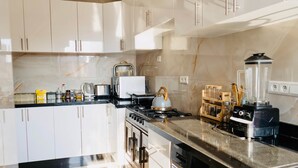 A modern kitchen with white cabinets, a stove, oven, and a blender on the counter. - A Luxurious, Modern, Central Gem + Netflix (Marrakesh)