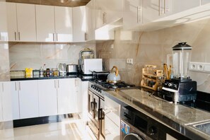 Eine moderne Küche mit weißen Schränken, einem Herd, einem Backofen und einem Mixer auf der Arbeitsfläche.