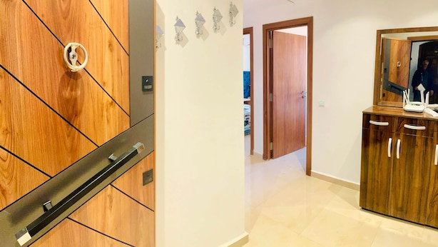 A hallway with a wooden wardrobe, a door, and a mirror reflecting a person. - A Luxurious, Modern, Central Gem + Netflix (Marrakesh)