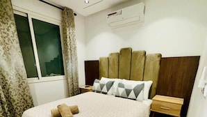 A modern bedroom with a large bed, a nightstand, an air conditioning unit, and a window with curtains. - A Luxurious, Modern, Central Gem + Netflix (Marrakesh)