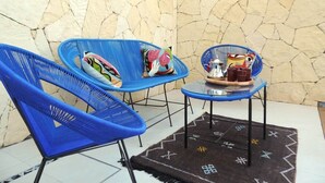 Una stanza con due sedie blu, un tavolino e un muro in pietra.