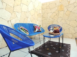 A room with two blue chairs, a small table, and a stone wall. - Modern villa with a private pool—Marrakech (Marrakesh)