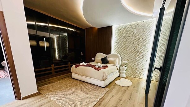 Una camera da letto moderna con un letto, comodini, un tappeto e una parete con motivo decorativo.