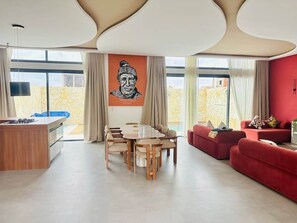 Un salon moderne avec une table à manger, des canapés rouges et une grande fenêtre donnant sur un beau paysage.