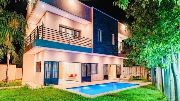 Une maison moderne à deux étages, dotée d’une piscine, d’un balcon et d’une entrée bien éclairée.