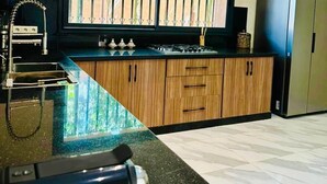 Une cuisine moderne dotée d’une grande fenêtre, d’appareils électroménagers en acier inoxydable et d’un plan de travail en marbre.