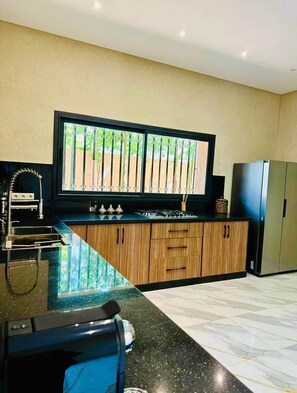 Cozinha moderna com uma janela grande, eletrodomésticos de aço inoxidável e bancada de mármore.