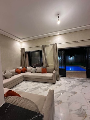Uma sala de estar moderna com um sofá seccional, uma piscina e uma grande janela.