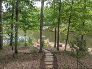 A forested area with a stone path leading to a dock over a calm lake. - Sunset Haven by Innsbrook Vacations! (Innsbrook)