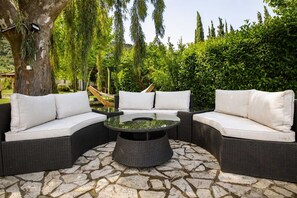 A curved outdoor seating area with a glass-top table and white cushions. - Blue Jasmine Villa - Private Pool and Garden (Aigialeia)