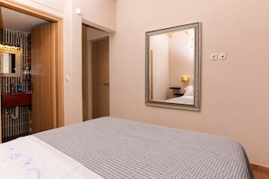 A hotel room with a bed, a mirror, a wardrobe, and a bathroom visible through an open door.