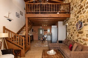Un vaste espace de vie agrémenté d’un escalier en bois, d’un mur en pierre et d’un coin salon confortable.