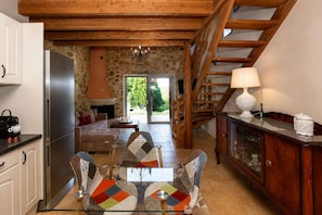 A kitchen with a refrigerator, dining table with chairs, a wooden cabinet, and a staircase leading to a living area.