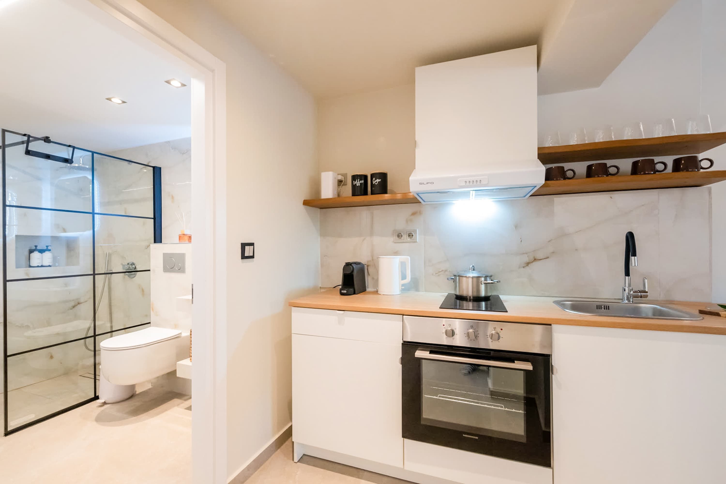 A modern kitchen with a built-in oven, a coffee maker, and a stainless steel sink.