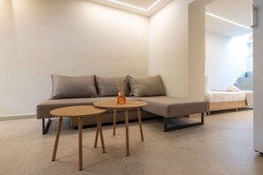 A modern living area with a sofa, two small tables, and a bed in the background. - Neilise - Modern Retreat in Central Kalamata (Kalamata)