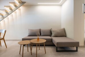 Ein modernes Wohnzimmer mit einer Couch, zwei runden Holztischen, einem Sessel und einer Treppe.