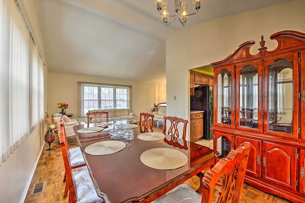 A dining room with a long wooden table, cushioned chairs, and a wooden cabinet with glass doors.