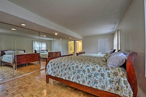 A bedroom with a wooden bed, a large mirror, and a wooden floor.