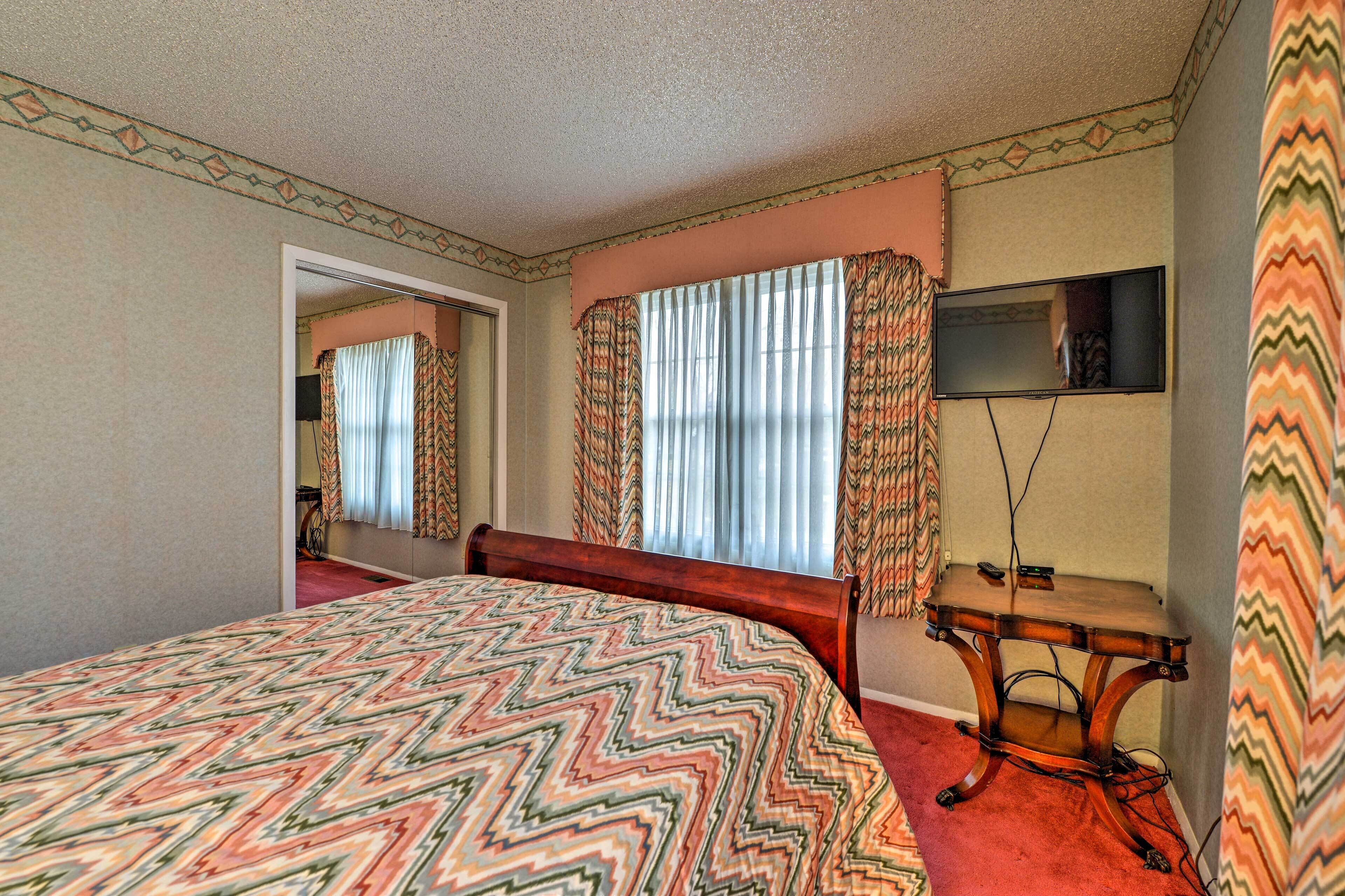 Un dormitorio con cama, escritorio, espejo y ventana con cortinas.