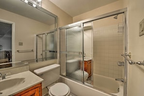 A bathroom with a glass-enclosed shower, a toilet, and a sink.