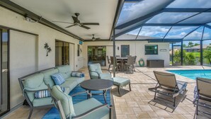 Eine überdachte Terrasse mit Pool, Gartenmöbeln und Deckenventilator.