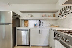 Una cocina moderna con electrodomésticos de acero inoxidable, lavavajillas, pileta y estufa.